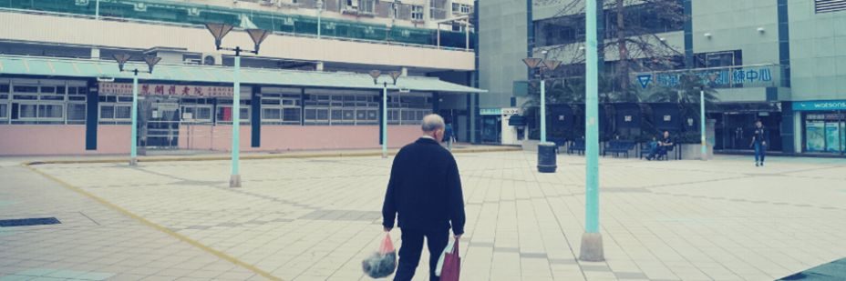 Un homme agé marchant dans la ville avec des sacs de courses.
